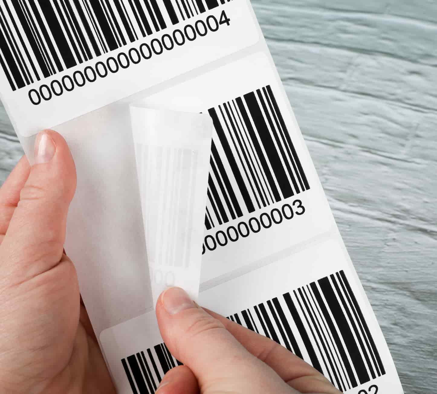 a hand peeling off a barcode label from a sheet