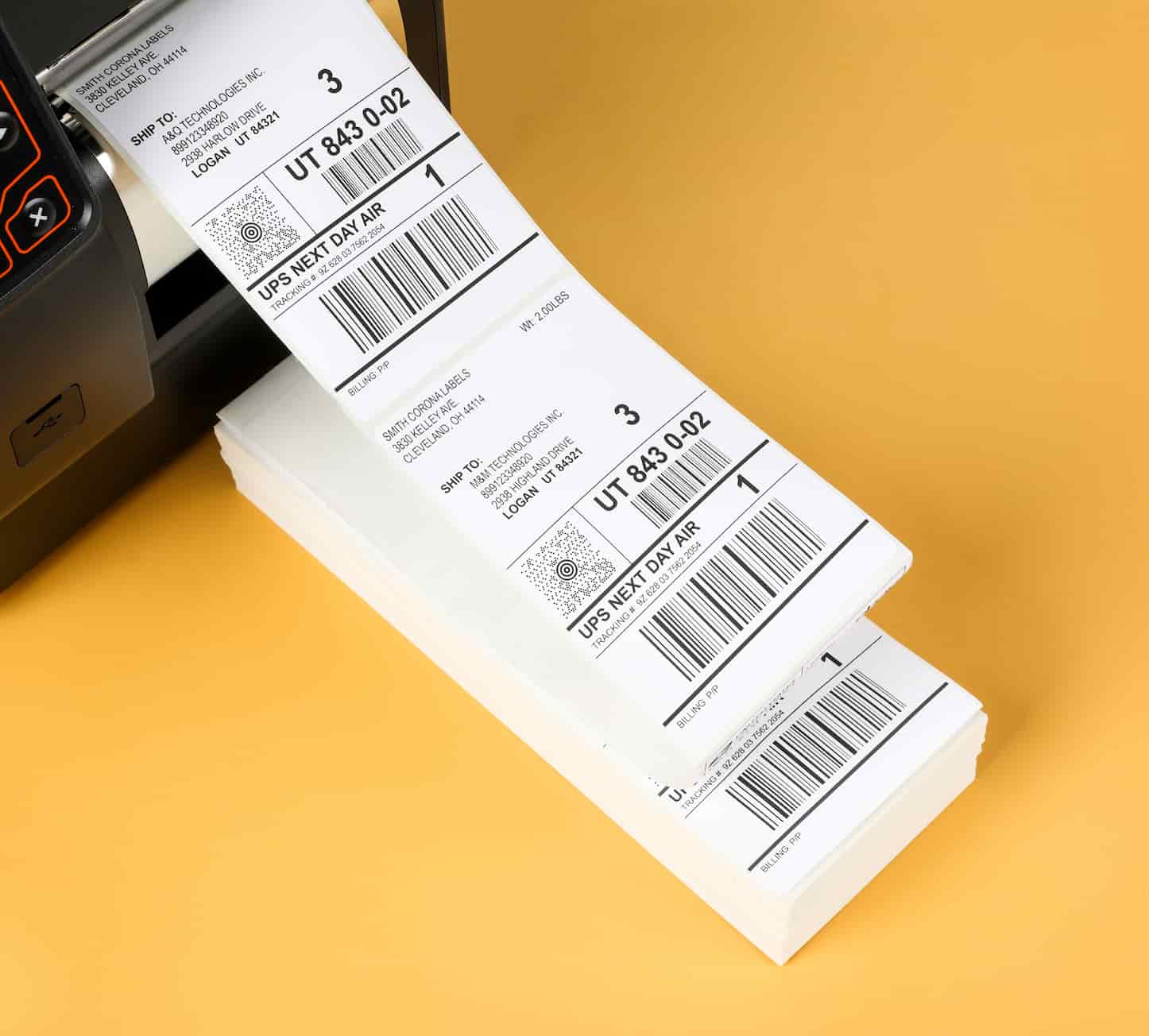 a stack of fanfold labels coming out of a printer