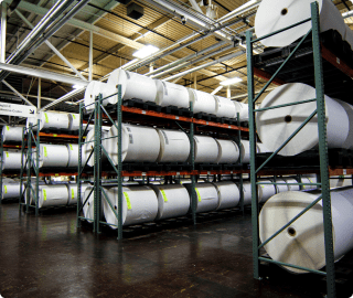Large inventory racks containing white master rolls of label material