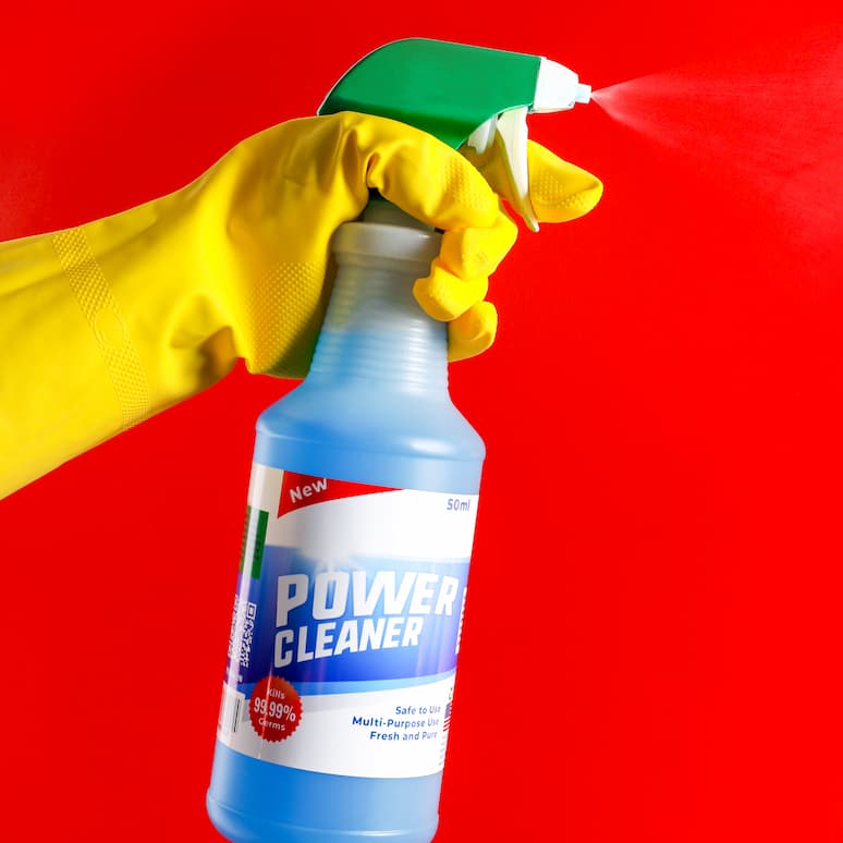 a gloved hand spraying a bottle of cleaner