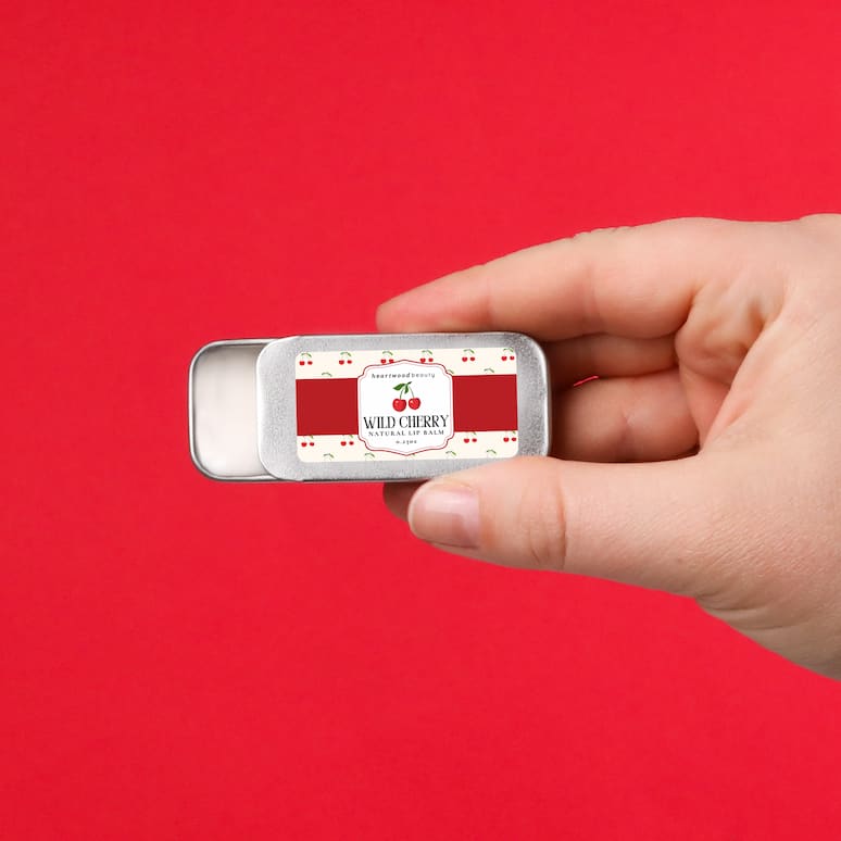 a hand holding a tin of wild cherry lip balm