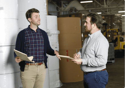 Smith corona team members conversing in front of stacks of raw materials