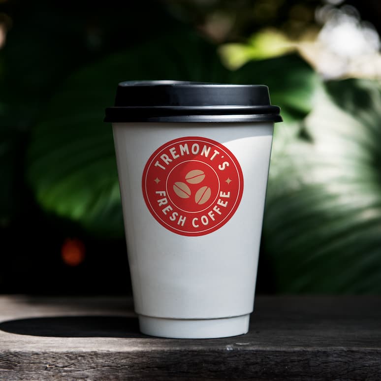 a labeled coffee cup sitting on a shaded table with giant leaves in the background