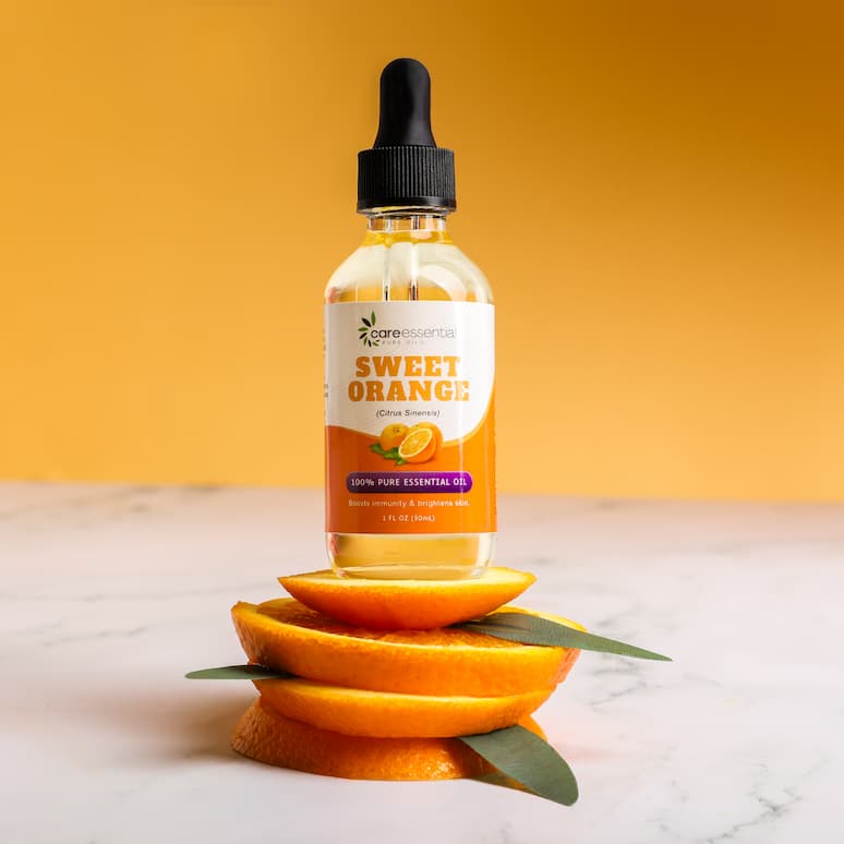 a bottle of orange oil sits atop a stack of orange slices and leaves