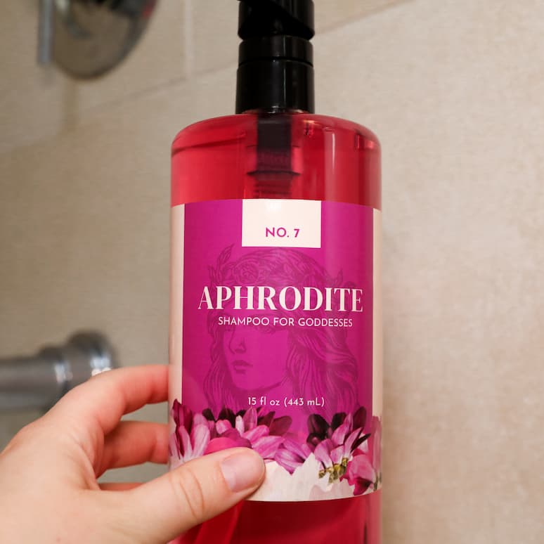 a hand holding a bottle of shampoo in a shower