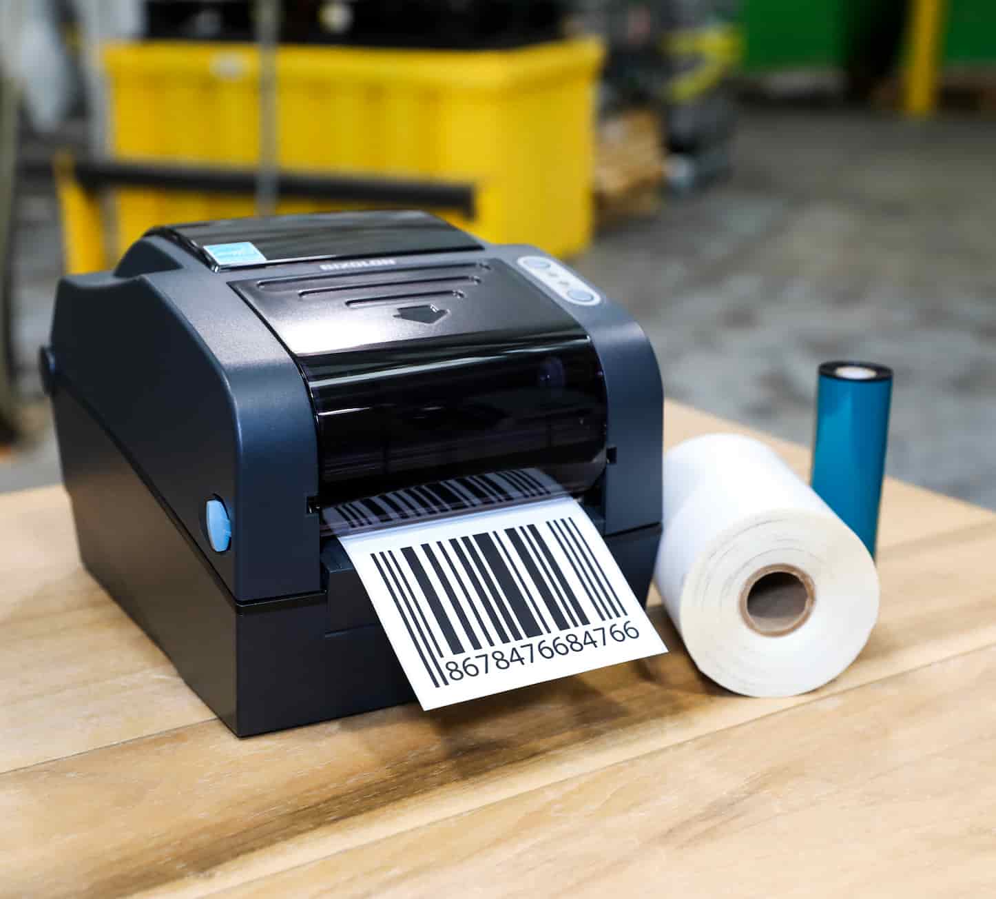 a hip printer next to a 1 in. core roll and thermal ribbon