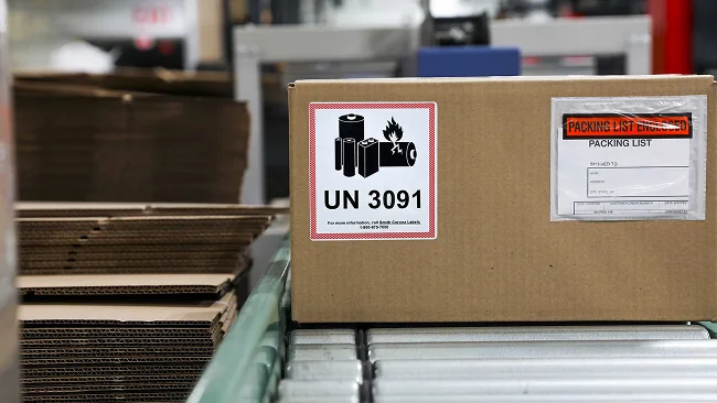 a battery warning label on a cardboard box on a conveyor belt