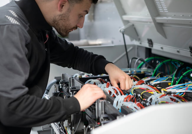 a man performing maintenance on a Bobst Digital Master Printing Press