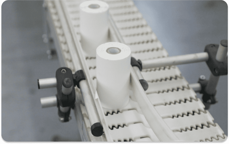 Two rolls of handheld printer labels moving across a conveyor belt