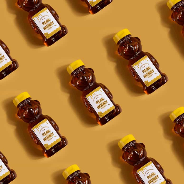 overhead shot of 3 rows of bear shaped bottles of honey facing up