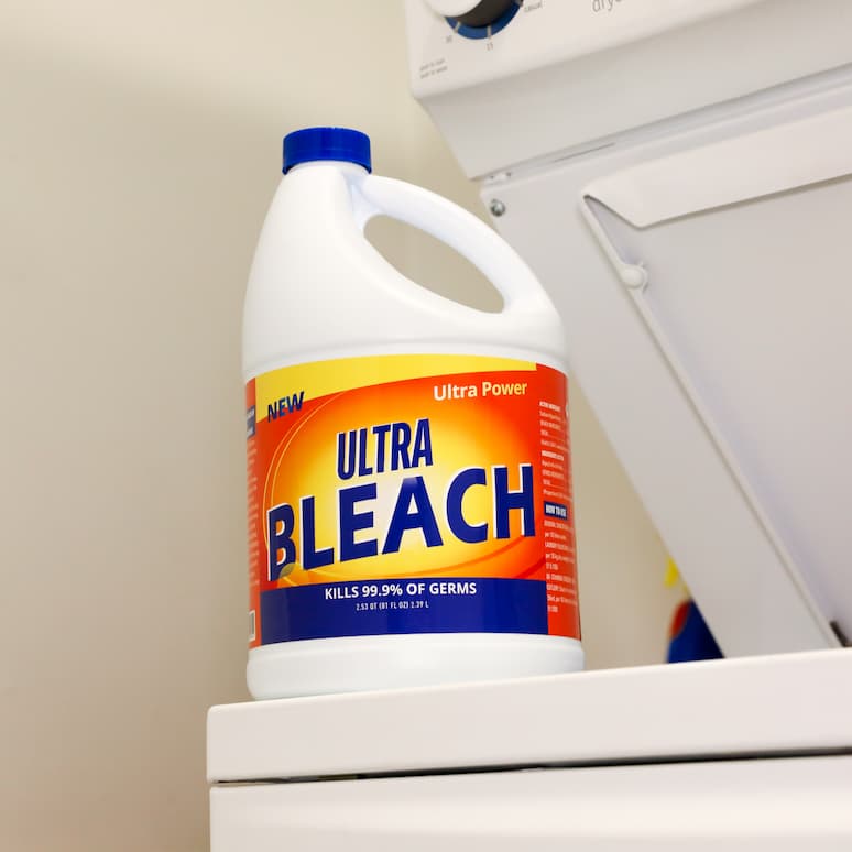 a bottle of bleach sitting on stop of a washing machine