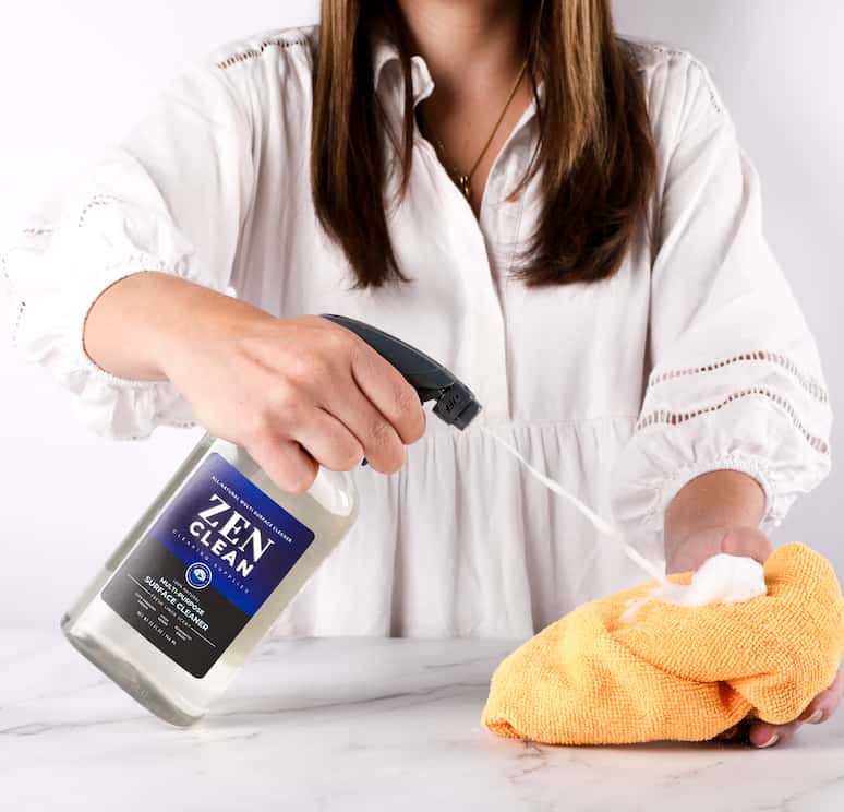 a woman spraying cleaner into a rag